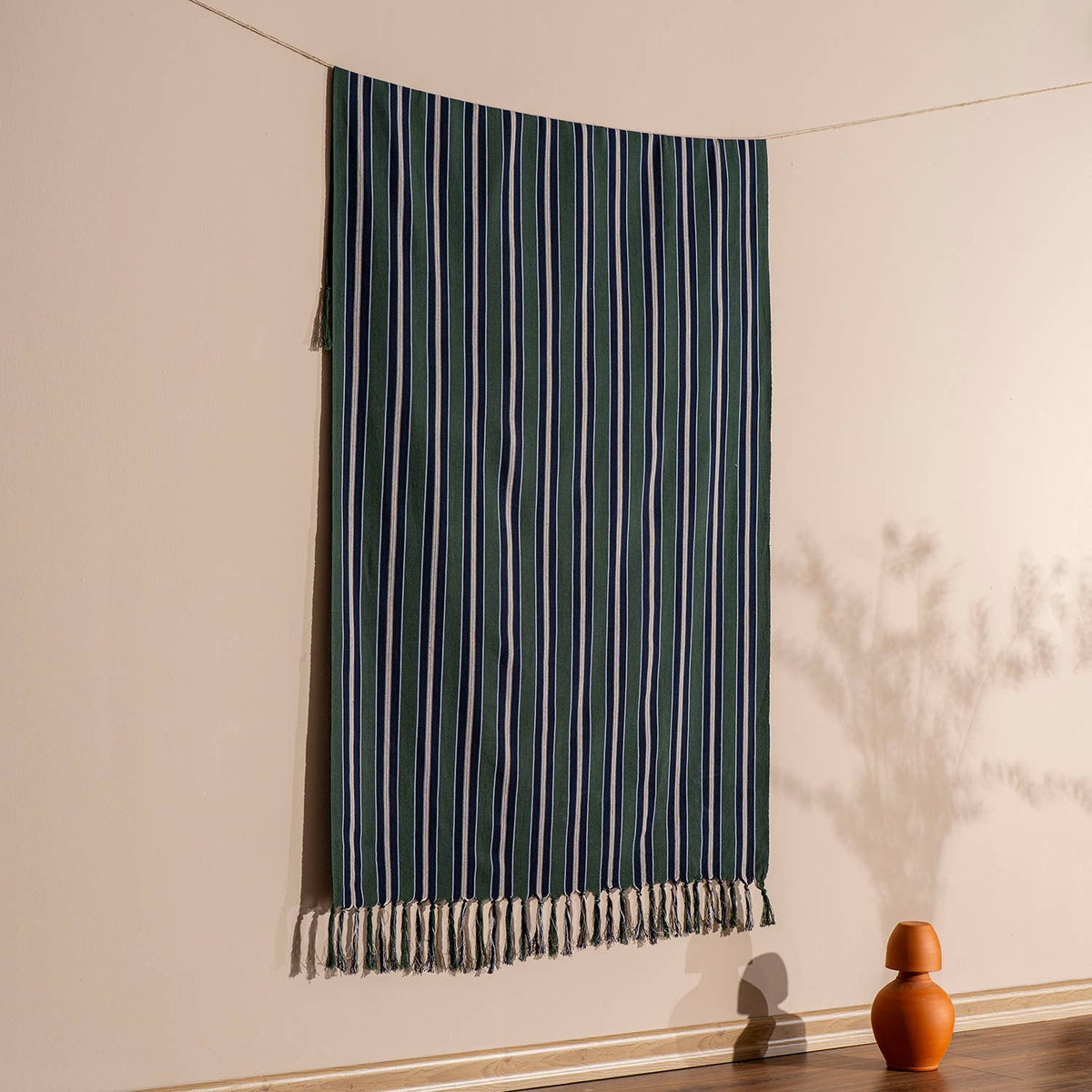 Forest green pinstripe Turkish beach towel hung against a warm wall | Kikoya