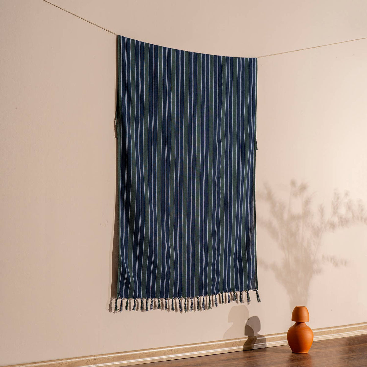 Ink navy pinstripe Turkish peshtemal hanging against a warm wall, 40x70 in | Kikoya
