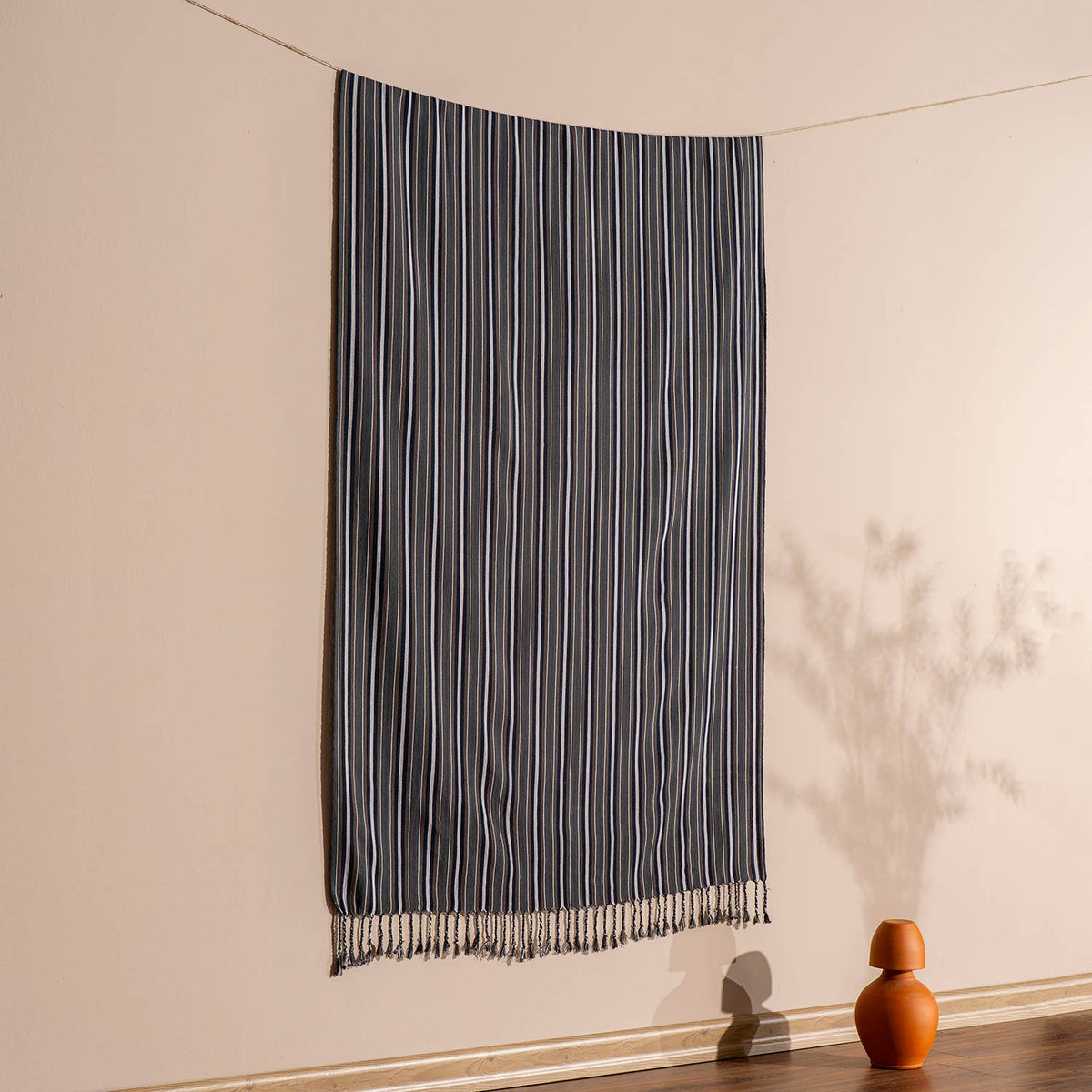 Graphite pinstripe Turkish beach towel hung against a warm wall | Kikoya