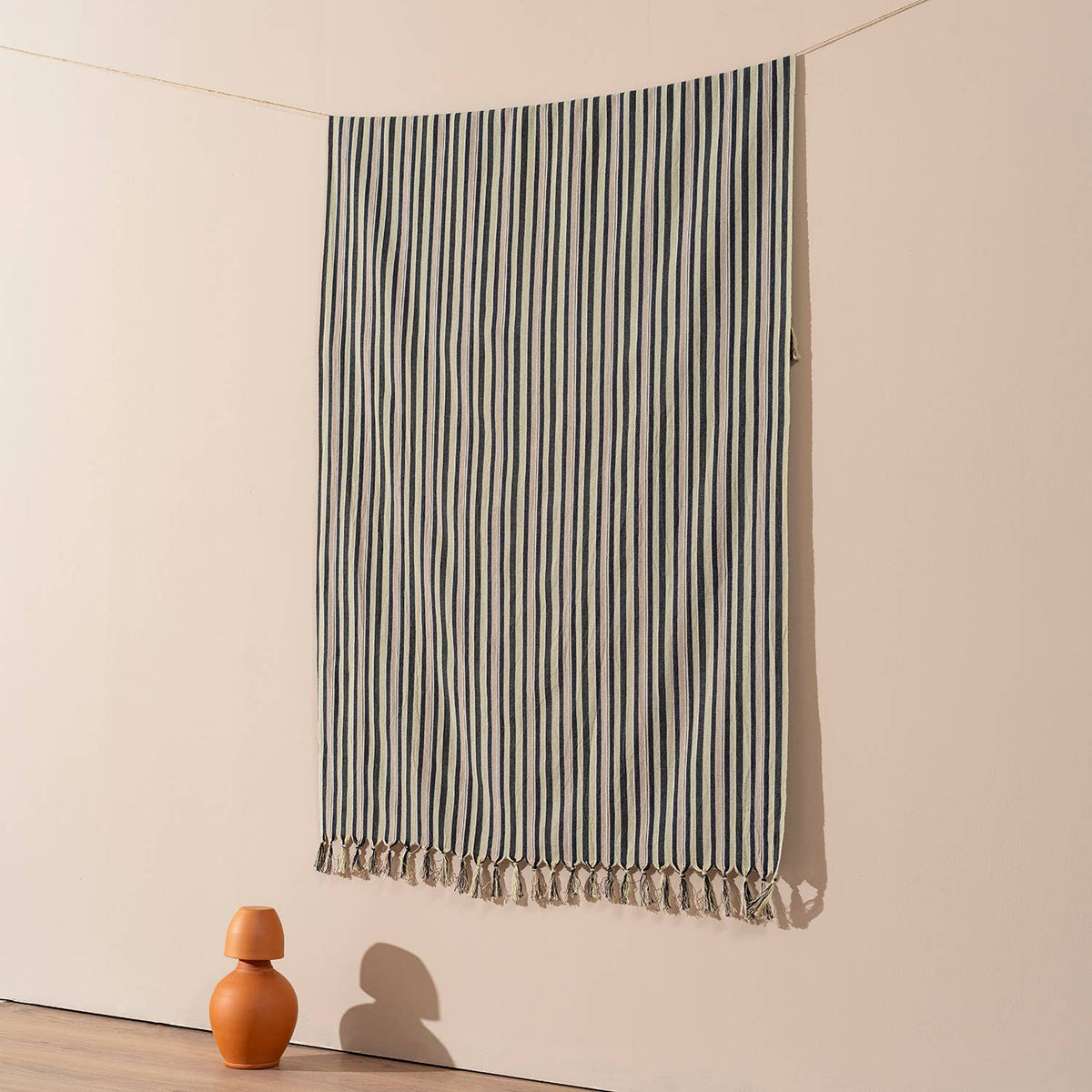 Charcoal ticking stripe Turkish beach towel hung against a warm wall | Kikoya