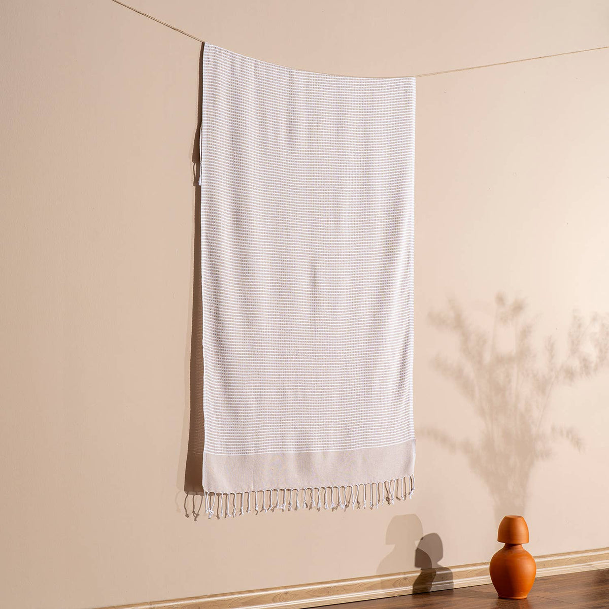 Beige Efes Turkish beach towel hung against a warm wall | Kikoya
