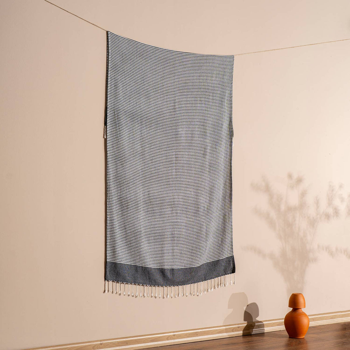 Black Efes Turkish beach towel hung against a warm wall | Kikoya